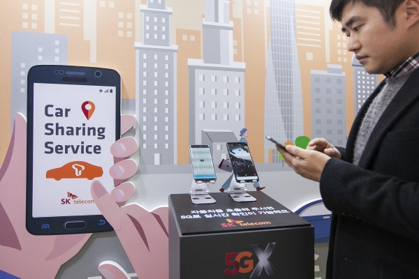SK텔레콤 연구원이 K-시티 준공식 행사에서 5G 카셰어링 자율주행차를 호출하고, 자율주행차가 스스로 달리는 모습을 5G 스마트폰 영상통화로 보고 있다.