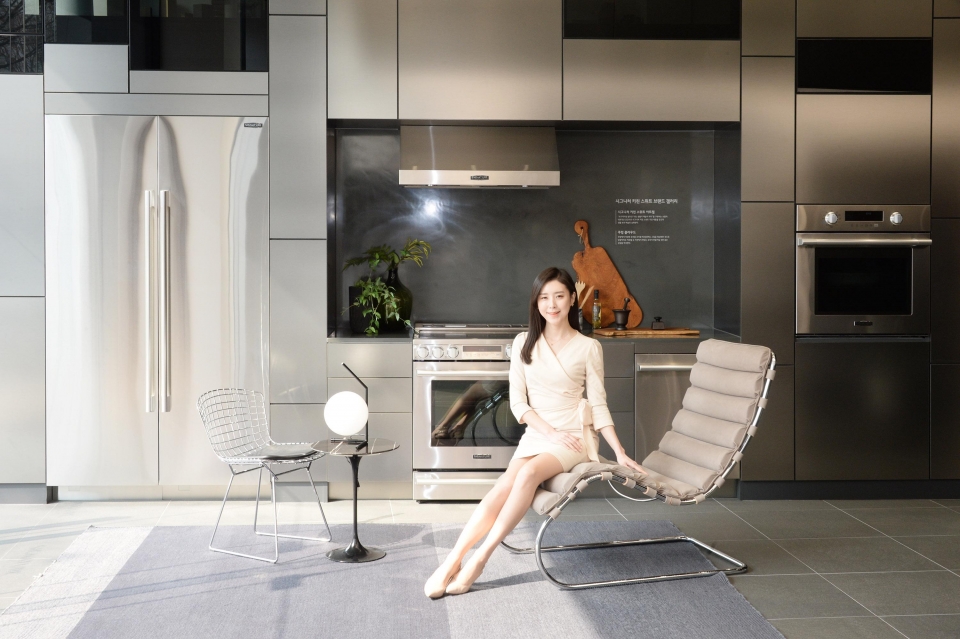 모델이 놀의 대표 제품 중 하나인 엠알 체어(﻿MR Chaise)에 앉아 가전과 가구가 조화를 이루는 주방 공간을 소개하고 있다.