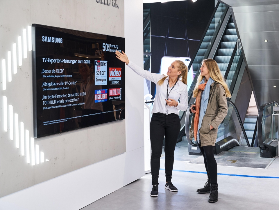 독일 프랑크푸르트 시내에 위치한 삼성 쇼케이스 매장에서 판매 직원이 고객에게 영상·음향기기 전문 매체들로부터 호평받은 QLED TV를 소개하고 있다.