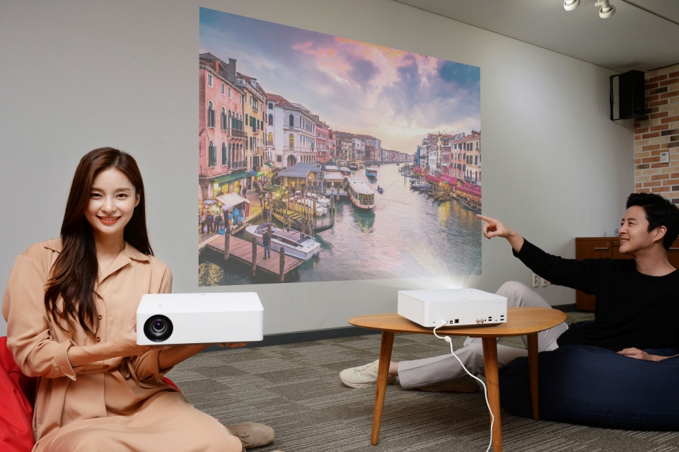 모델들이 'LG 시네빔 4K' 프로젝터가 구현하는 초대형 화면으로 영상을 즐기고 있다.