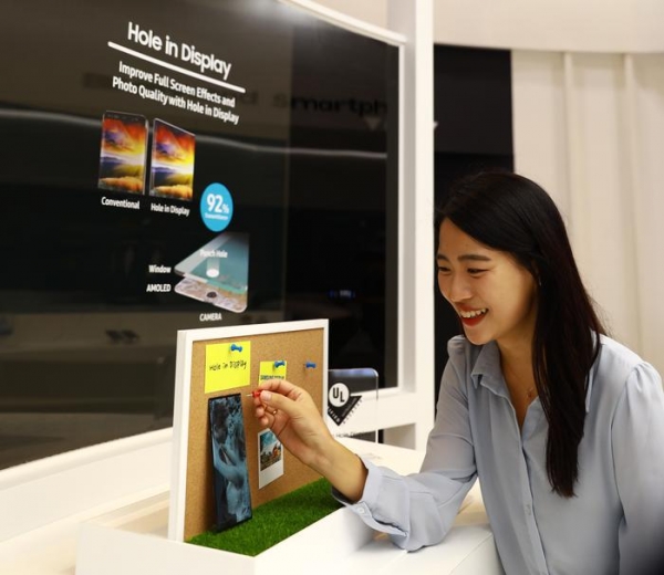 삼성디스플레이 직원이 'IMID 2019'에서 플렉시블 OLED로 구현한 홀디스플레이를 체험하고 있다.